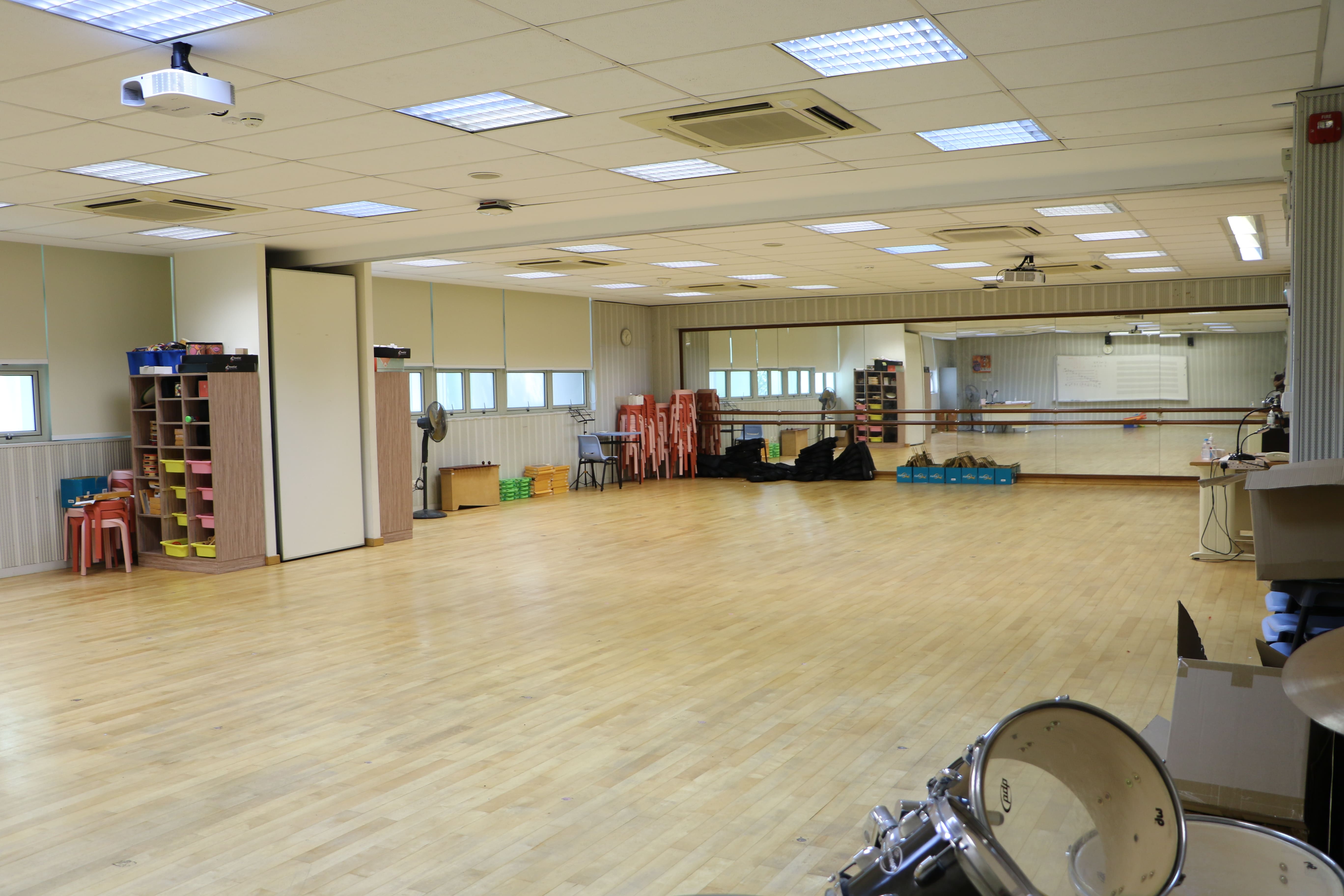Spacious music room with wooden flooring, mirrors and musical equipment.